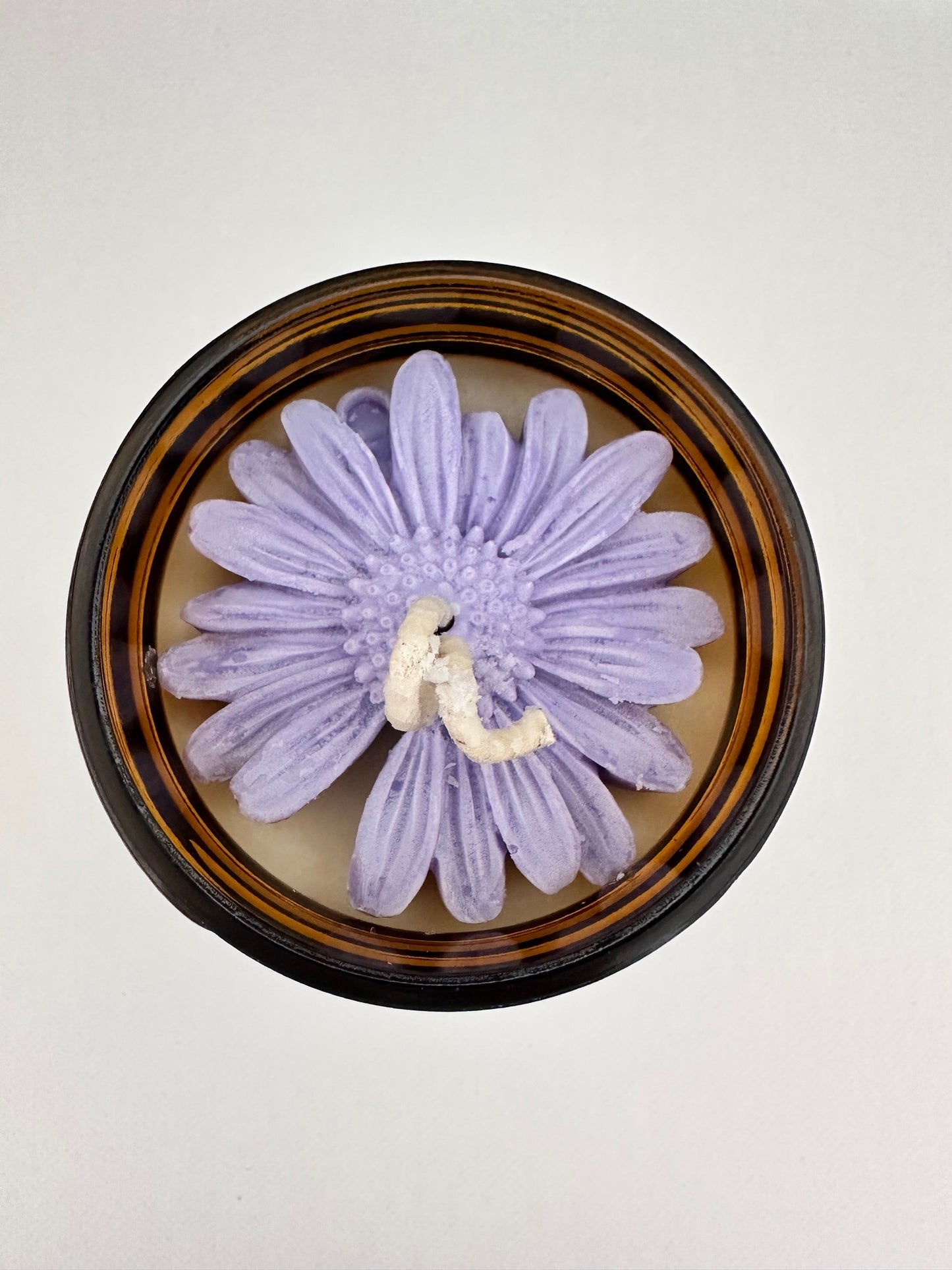 Close-up of a soy wax candle topped with a large, intricate flower, showcasing the elegant floral design integrated into the candle.